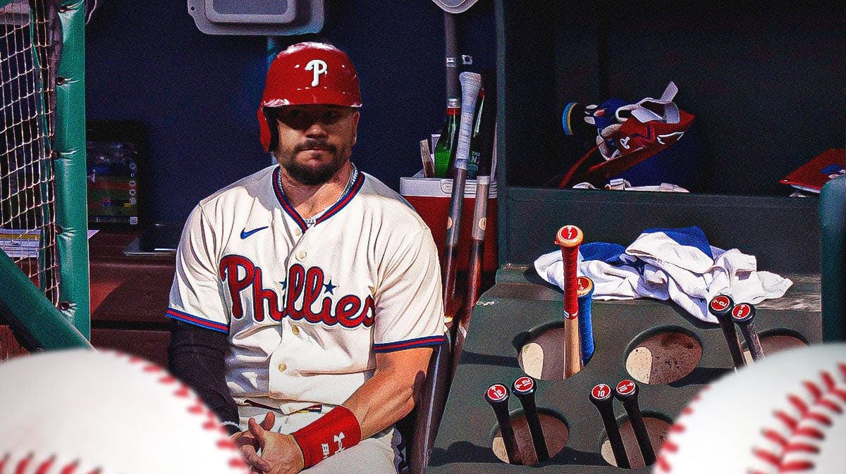 Phillies' Kyle Schwarber sitting down in an MLB dugout looking serious.